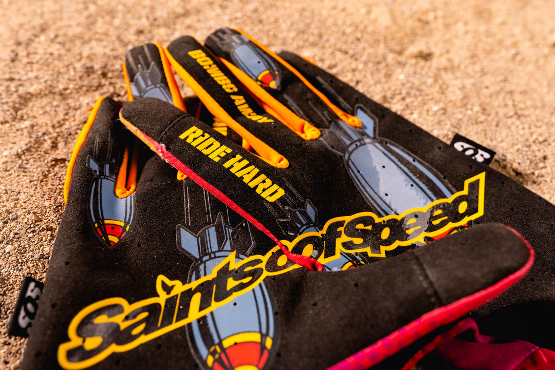 A close-up of Saints of Speed riding gloves showing the palm construction and printed details