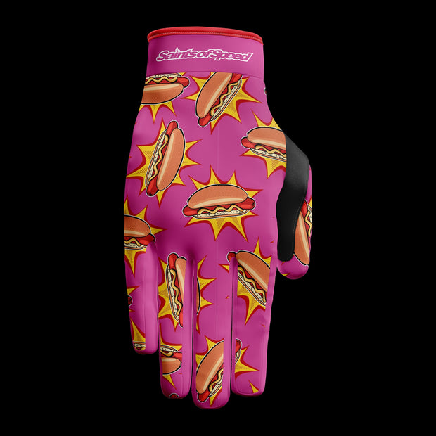 Motocross gloves with a vibrant pink design featuring bold hot dog graphics and "Saints of Speed" branding.